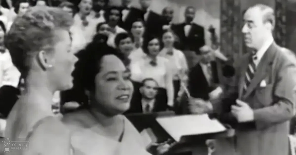 A wedding ceremony taking place indoors with a crowd seated in the background.