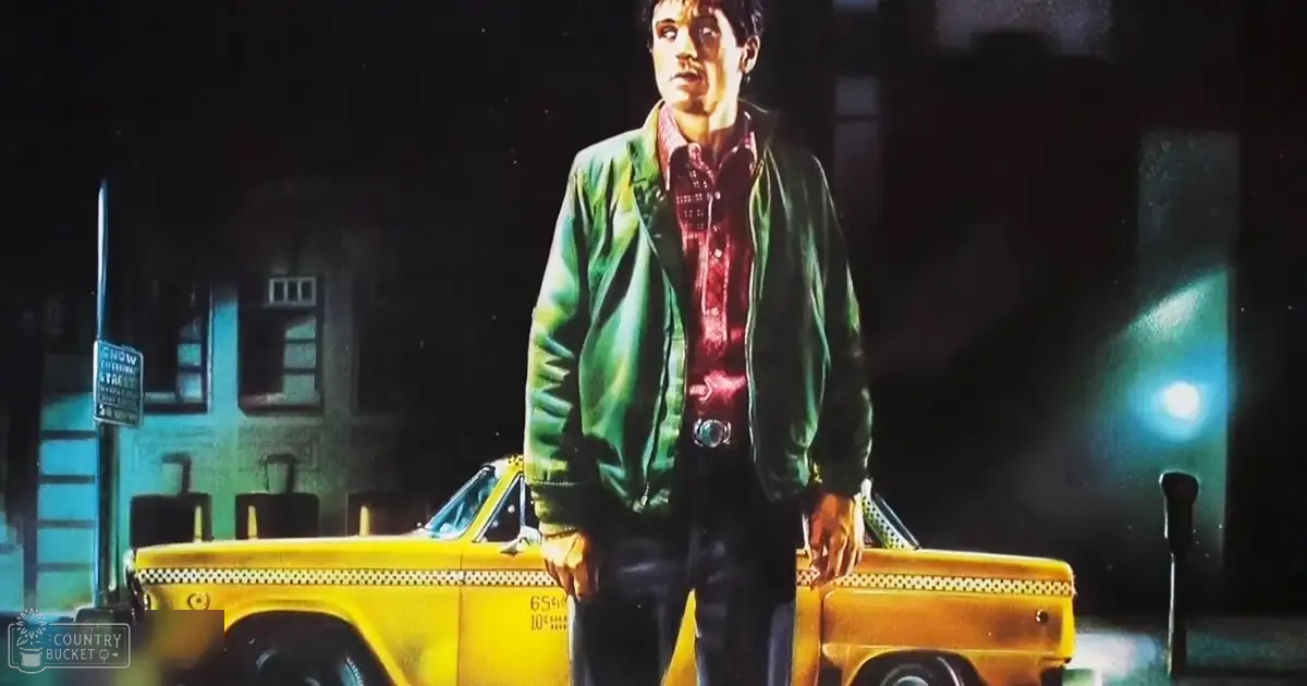 A young adult male in an urban setting, wearing a green bomber jacket over a red plaid shirt and dark pants, standing near a yellow taxi cab with 'NOW' partially visible on a signpost.