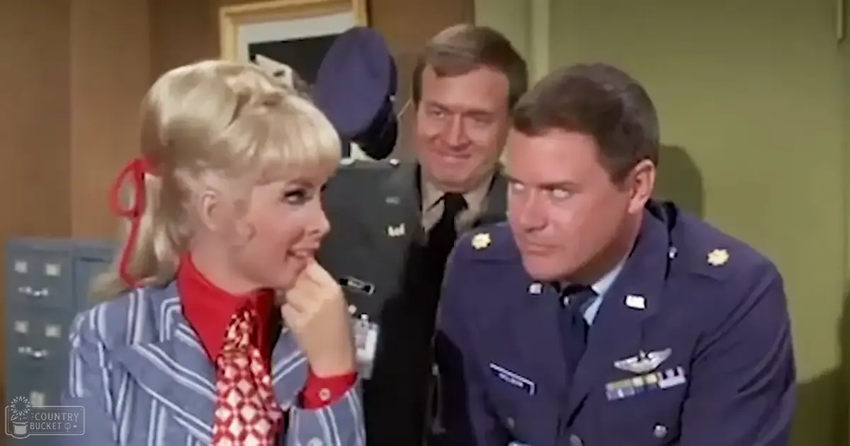 Adult female wearing striped blue and white blazer with red shirt underneath, standing indoors with two middle-aged men in military uniforms.