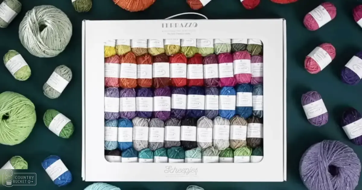 A white box labeled 'TERRAZZO' containing neatly arranged skeins of colorful yarns in various shades, indoors with a dark teal background.