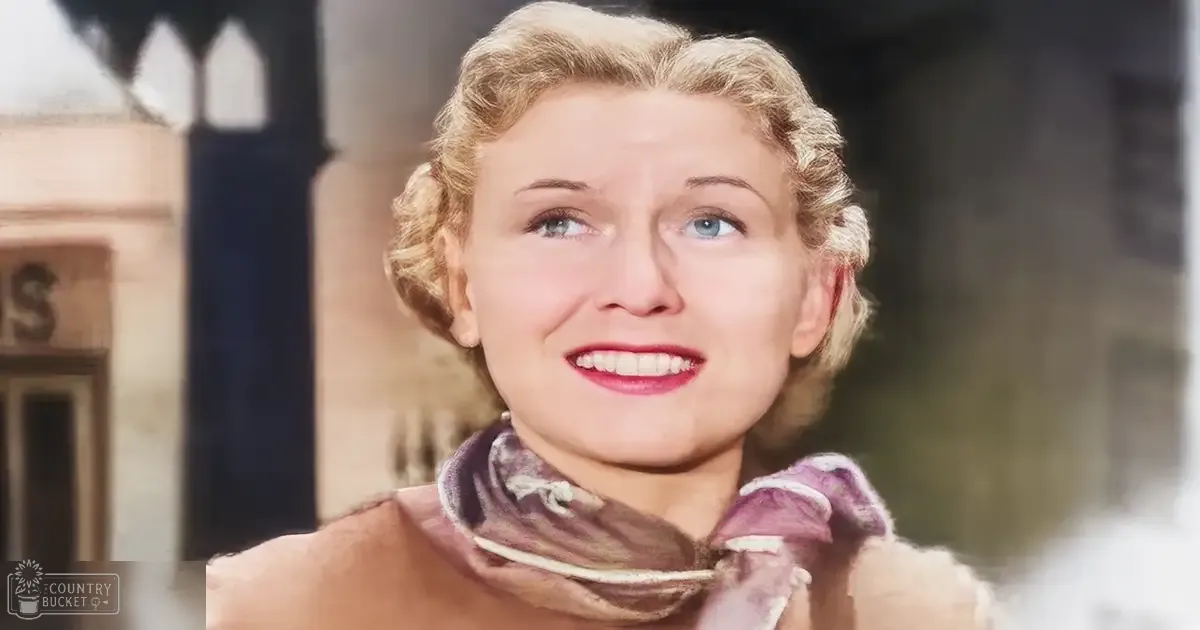 A middle-aged woman wearing a scarf with 'Madly Odd' written on it, standing outdoors in what appears to be an urban setting during daytime.