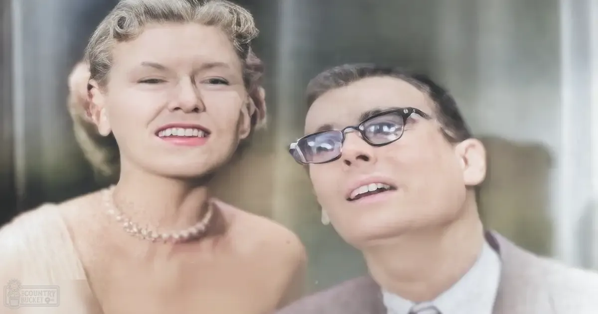 Middle-aged woman wearing a delicate necklace and light-colored dress indoors near a young adult man in an elevator setting during the daytime with neutral tones.