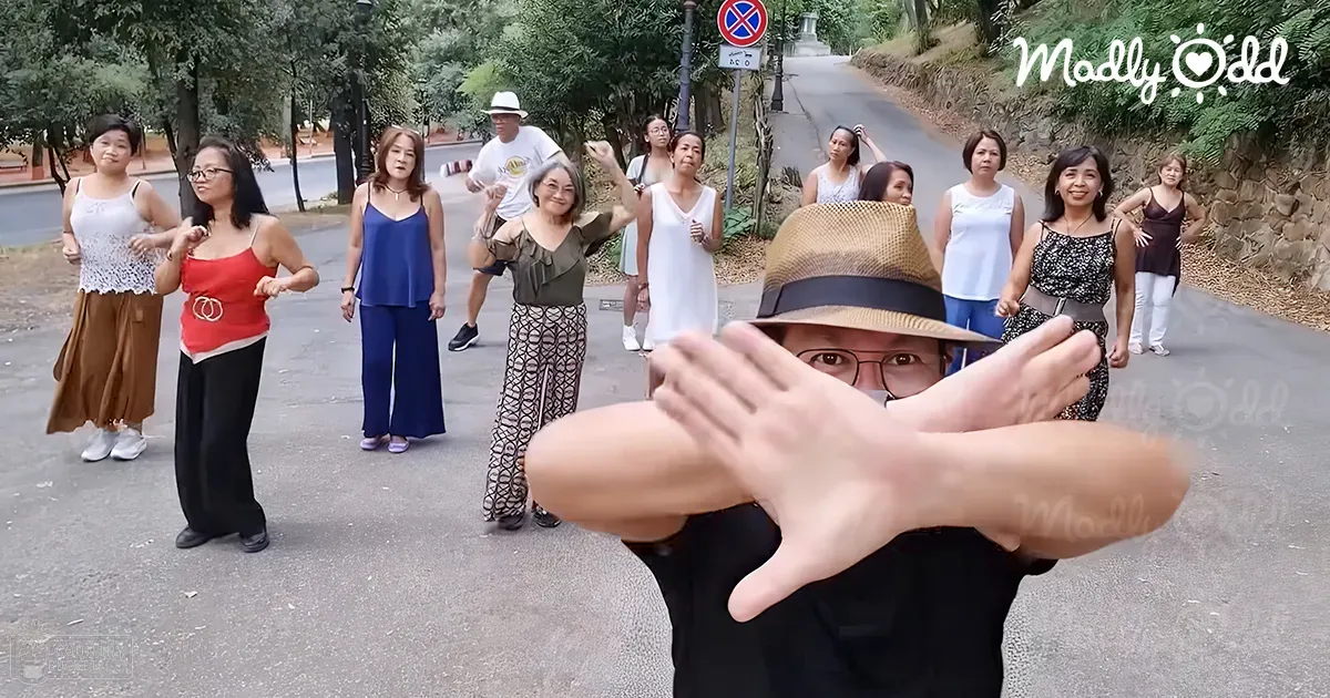 Adults gathered on a paved road surrounded by lush greenery under soft daylight, possibly late afternoon.