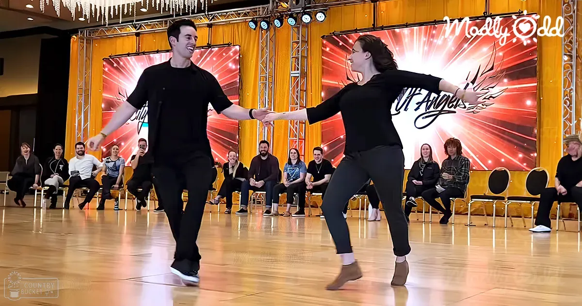 A dance performance in an indoor venue with young adult male and female dancers wearing casual attire; audience seated casually in rows facing the stage.