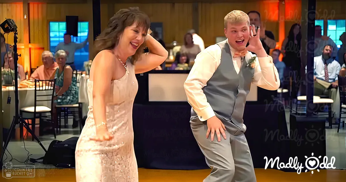 A couple dancing at an indoor wedding reception with warm beige and cream tones, wooden paneling, and blue lighting accents.