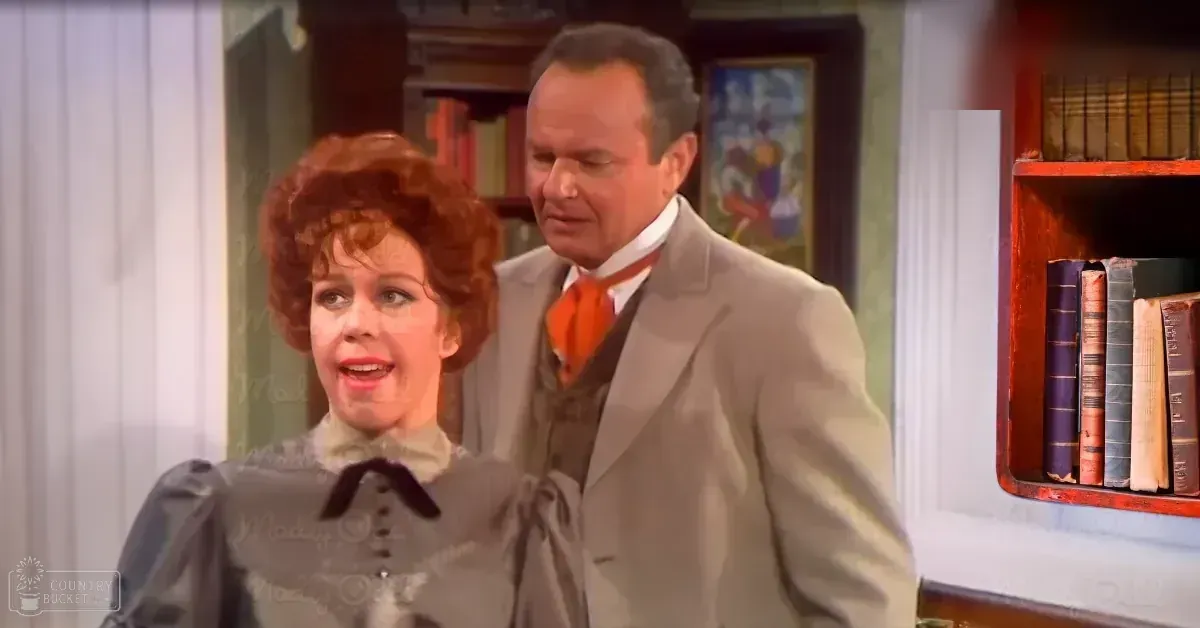 Adult female in Victorian-style dress with puffed sleeves and a bow at the neckline, interacting with an adult male wearing a light-colored suit and orange tie in a historical indoor setting with furniture like a red bookshelf and framed artwork.
