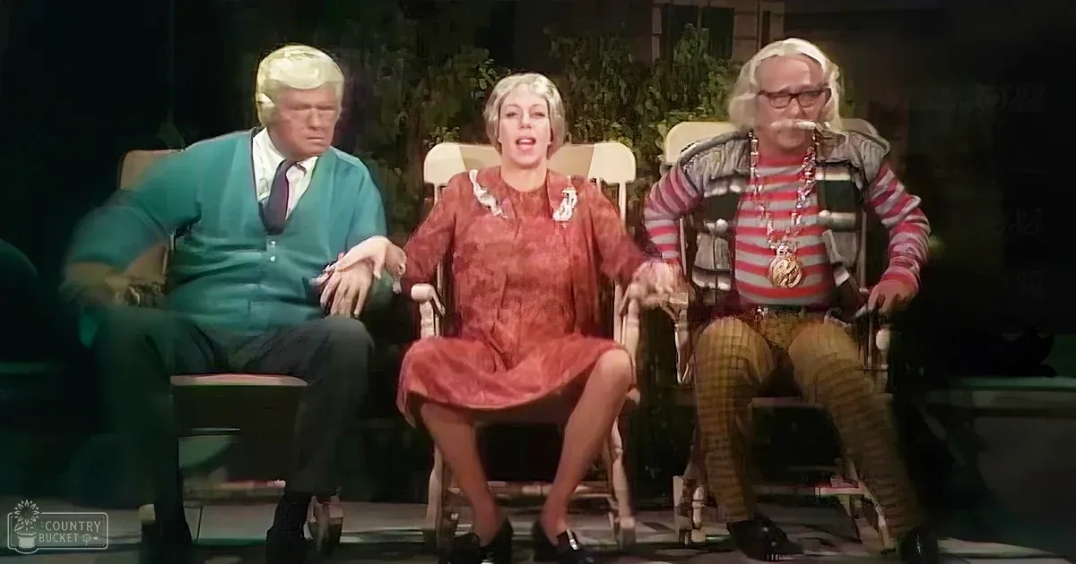 A comedic skit scene with three individuals seated indoors against a backdrop of greenery and a 'Madly Odd' logo.