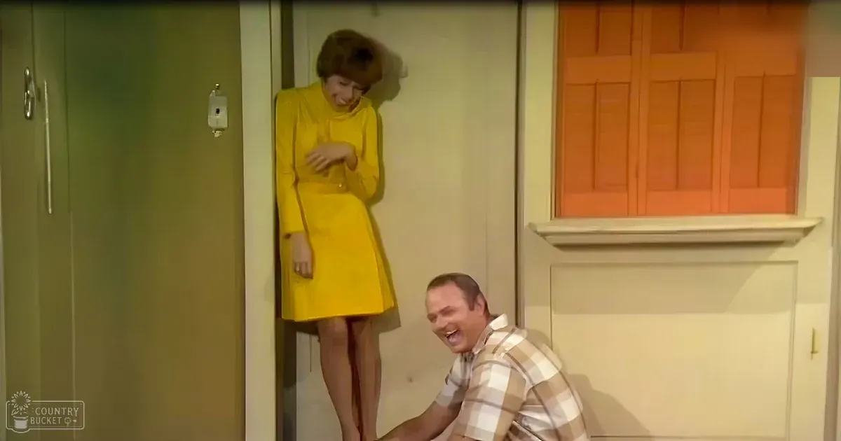 A comedy sketch scene with a bright yellow dress and plaid shirt, set against a green door and orange cabinet.
