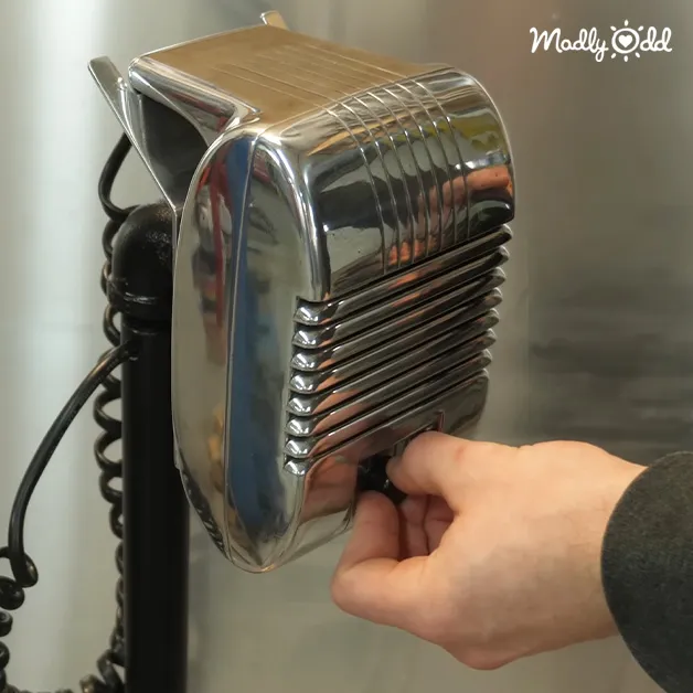 A vintage microphone with a shiny, reflective surface against an indoor neutral background.
