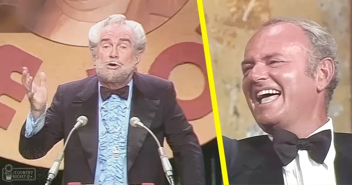 Formal event attire: older adult male in dark suit jacket and patterned bow tie; younger adult male in black tuxedo, stage setup with microphones suggests awards ceremony or similar occasion.