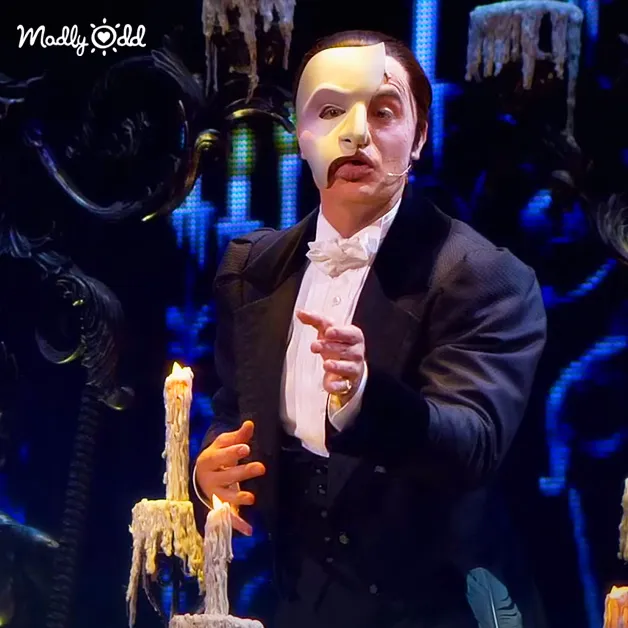Phantom songs performed, singer in costume, dramatic lighting enhancing the scene.