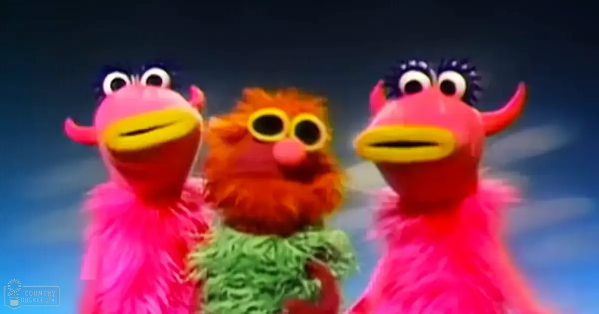 Three puppet characters from Sesame Street in a simple blue gradient background, likely indoors with artificial lighting.