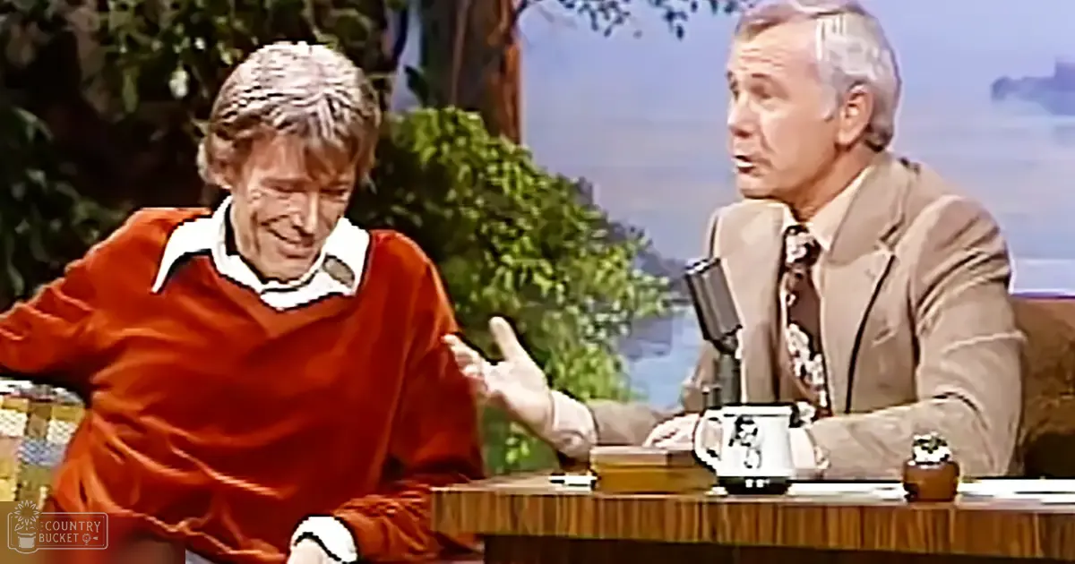 Adult male guests on a talk show set with wooden furniture, plants, and bright lighting.