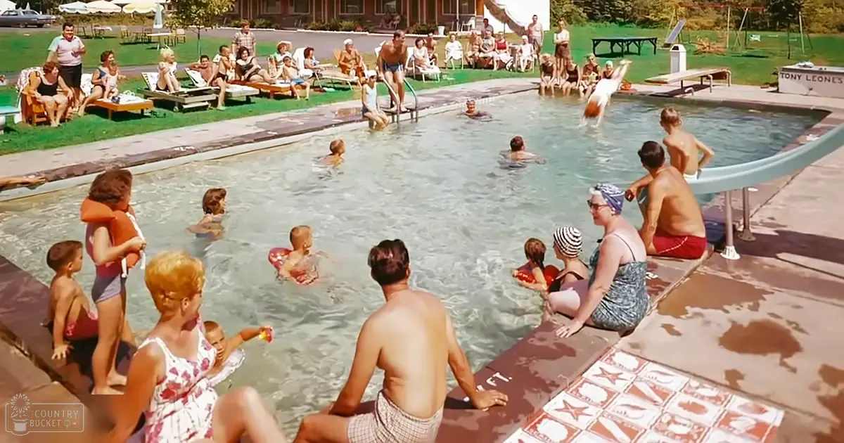 A mid-20th-century outdoor swimming pool scene with various age groups of people in swimwear, lounge chairs, and a sign reading 'TONY LEONE'S' under clear blue water.
