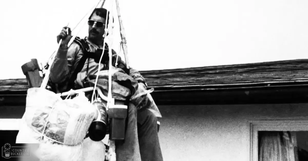 An adult male in an urban work uniform with protective gear, working on a rooftop or elevated structure during daytime.