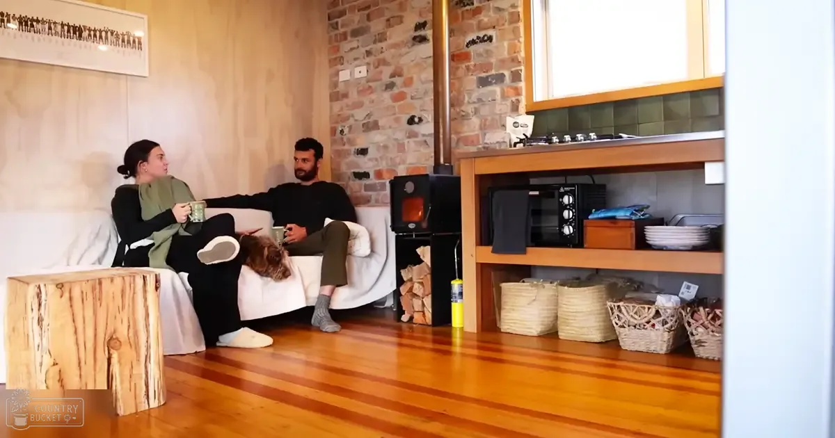 A cozy living room scene with two adults sitting on a white couch indoors during daytime.