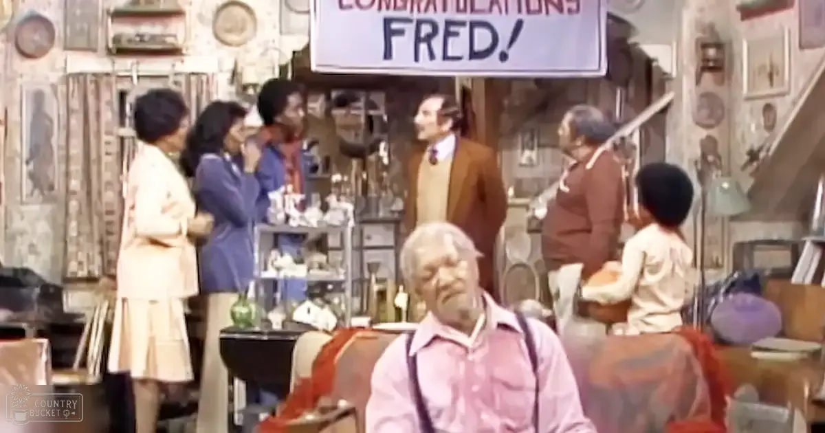 An older adult male in a light pink shirt and dark suspenders sits at a diner table, surrounded by other patrons in casual attire. The cozy setting includes shelves with decorative items and a sign reading "CONGRATULATIONS FRED!"