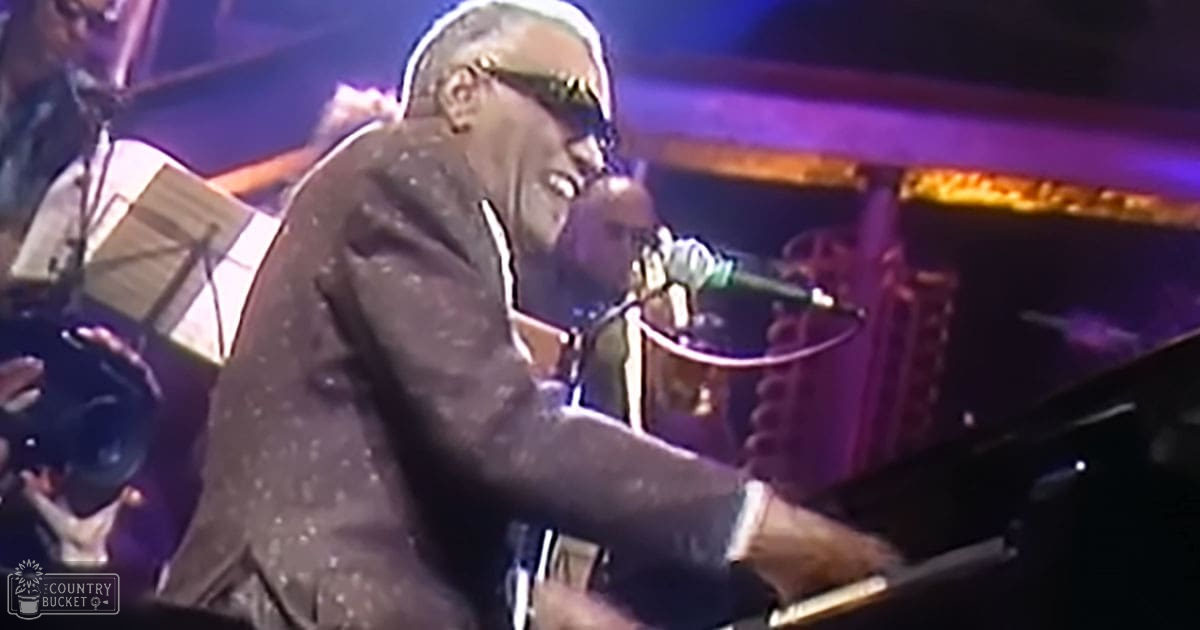 An older adult male performer singing and playing piano on stage during a live concert.