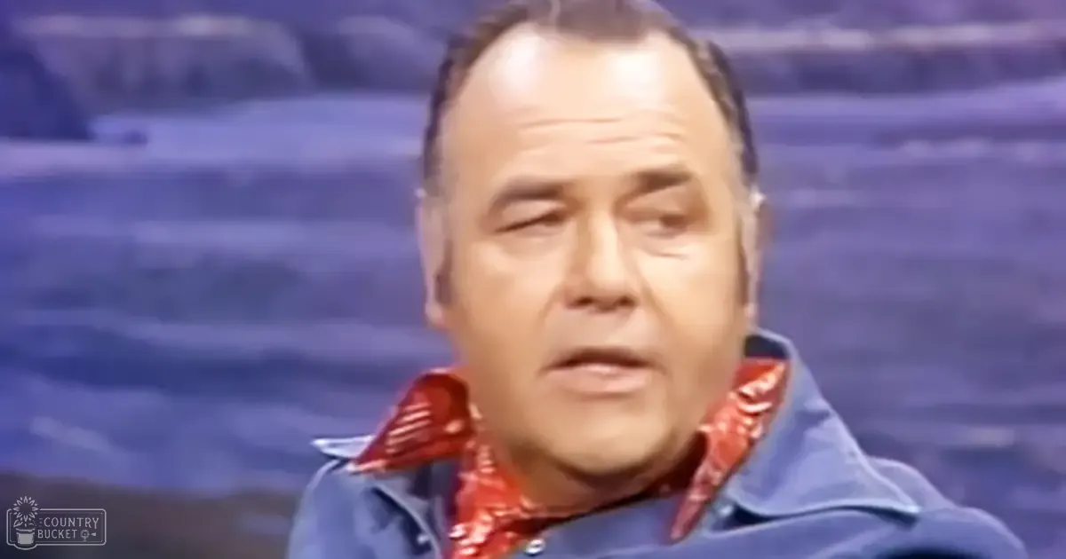 An older adult male wearing a relaxed fit, button-up shirt with a red patterned collar and cuffs in a studio setting.