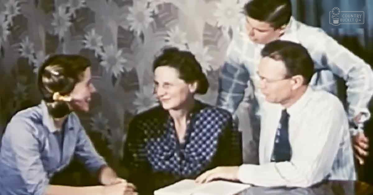 Five adults in an indoor setting with floral wallpaper and natural light, possibly spring or summer.