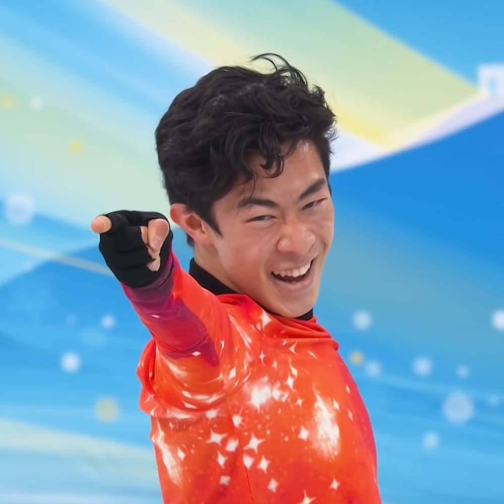 A young adult male in red athletic wear with white star patterns celebrates at what appears to be a sports event.