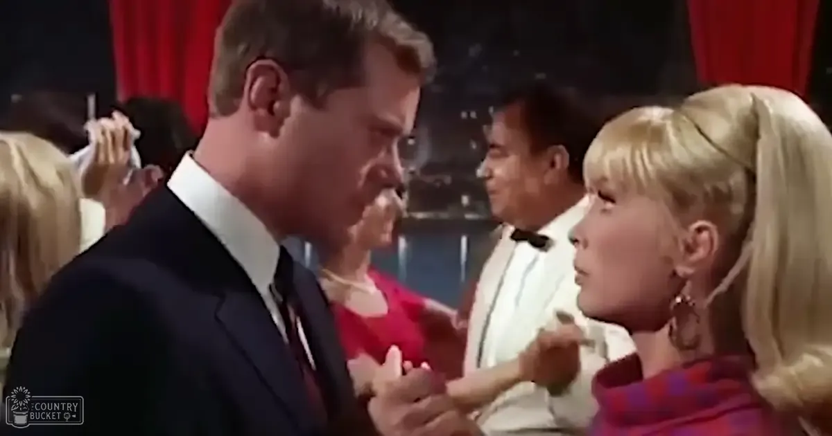 A formal event scene with individuals dressed in elegant attire, set against a red curtain backdrop under artificial stage lighting.