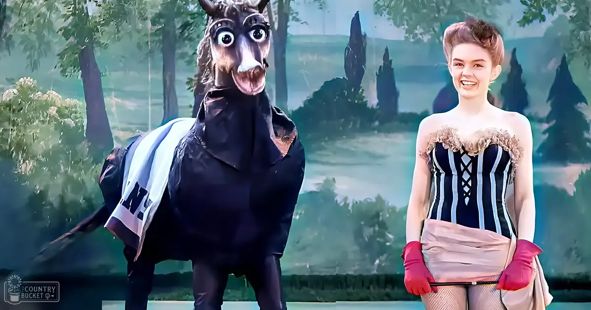 A person in a black and white donkey or horse costume interacts with another individual wearing a striped corset and pink skirt amidst lush green forest foliage, suggesting daytime during spring or summer.