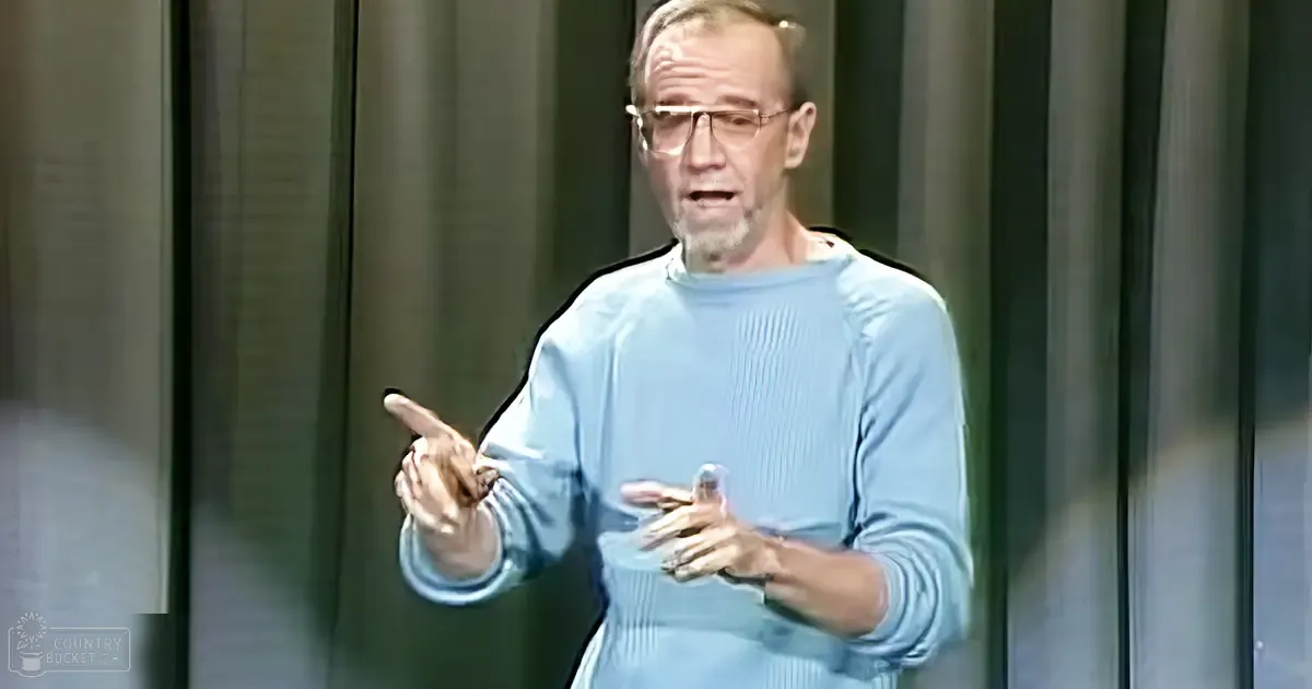 A middle-aged adult male gives a presentation in an indoor setting with controlled lighting.