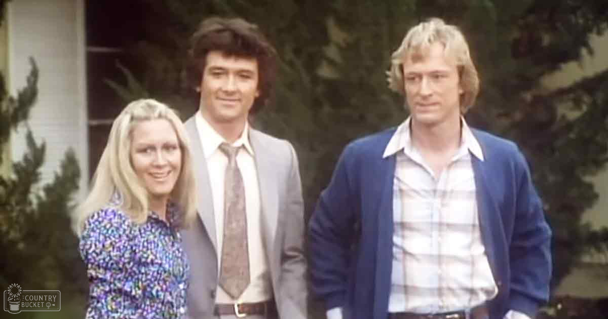 Group photo taken in front of a residential building with trees and shrubs visible; late 1960s or early 1970s style clothing.