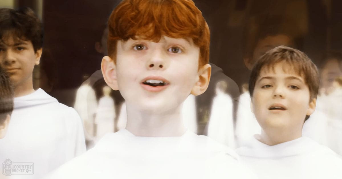 Young boys in choir robes performing in a softly lit indoor setting, possibly during daytime.
