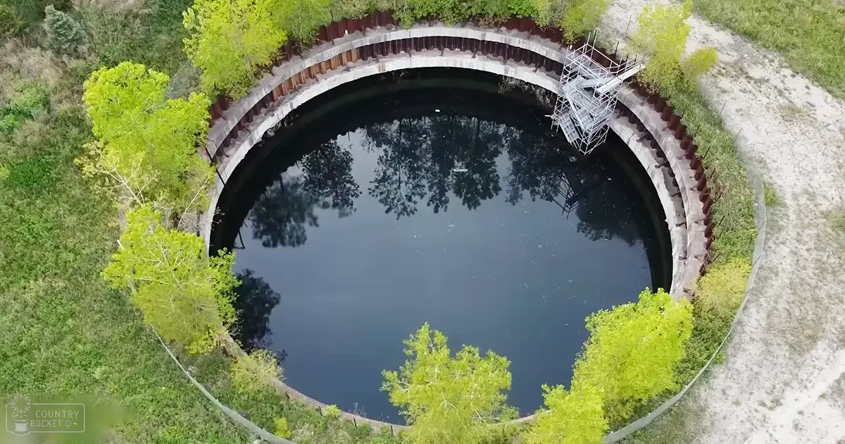 A natural setting with a circular water feature, surrounded by trees in an outdoor environment during daytime.