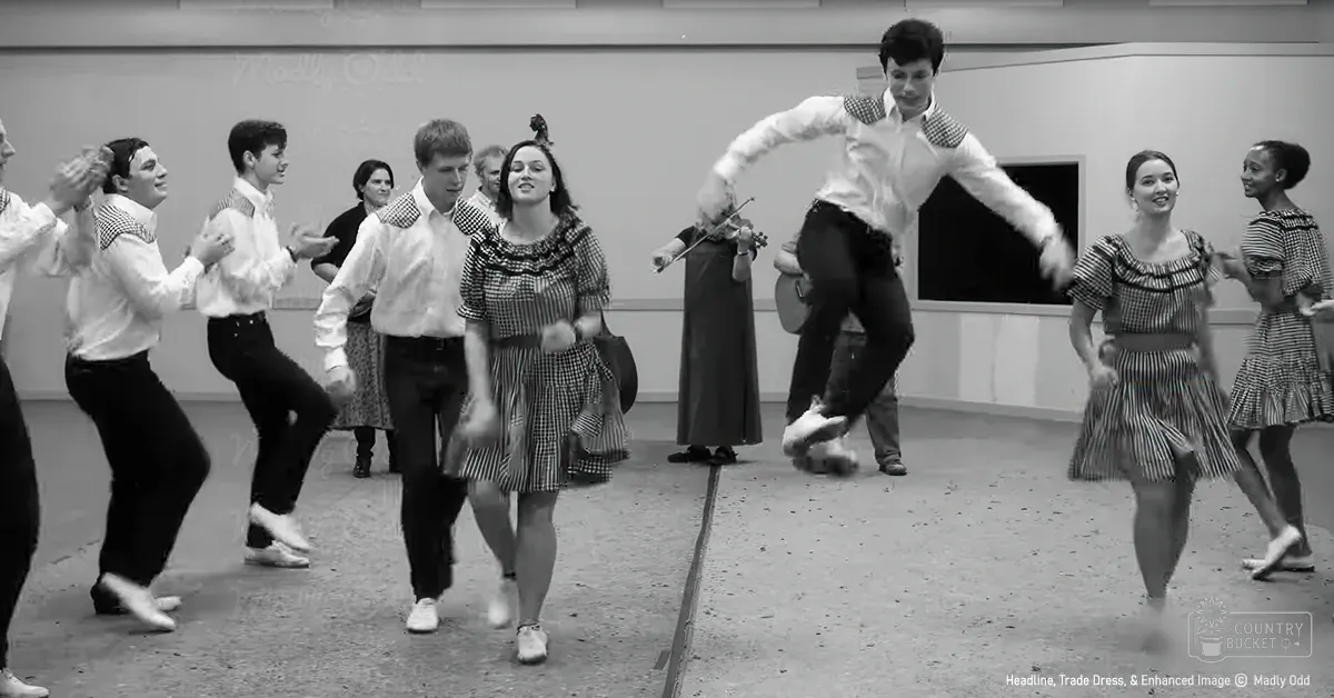 Teenagers in a dance class wearing checkered shirts and adults in patterned dresses, set indoors with simple walls and a chalkboard.