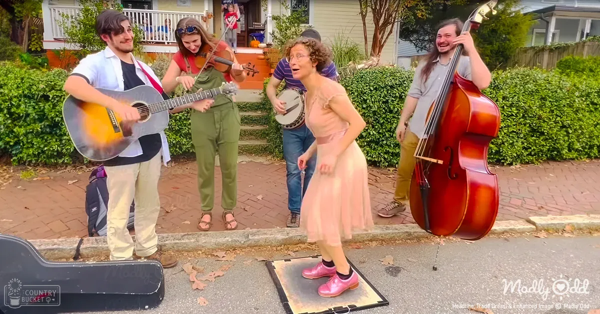 Young adults perform street music in front of a house on a clear day with greenery and residential surroundings.