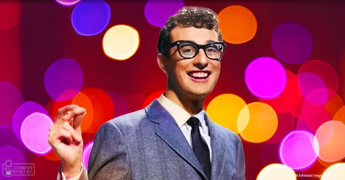 A young adult male in a tailored blue suit jacket and white shirt with a black tie stands against colorful bokeh lights in an indoor setting with 'Madly Odd' text visible.