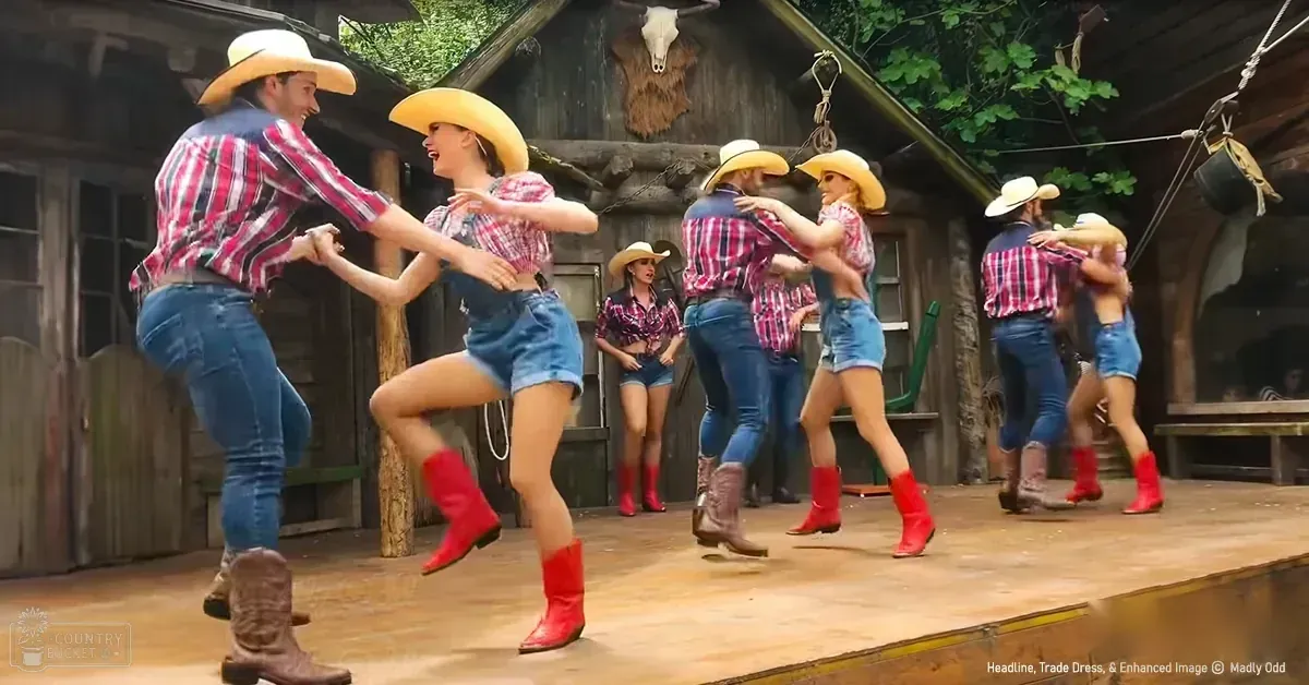 A group dancing in a rustic setting, likely at an amusement park or themed attraction.