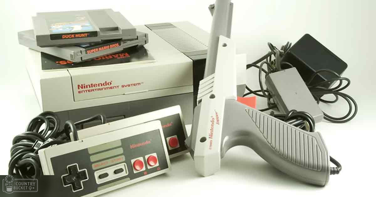 A Nintendo Entertainment System gaming console with accessories, including game cartridges, a controller, a Zapper light gun, and a power adapter, displayed indoors under artificial lighting.
