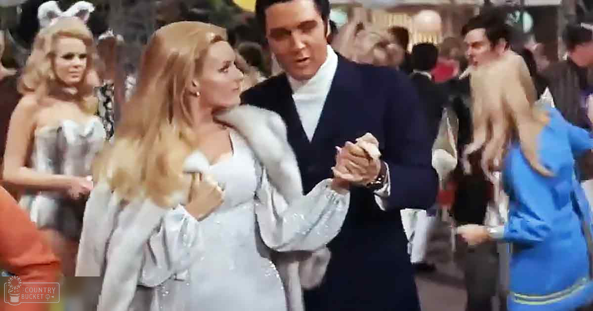 A couple dancing in a classic film-era indoor ballroom, wearing formal attire with bright lighting.