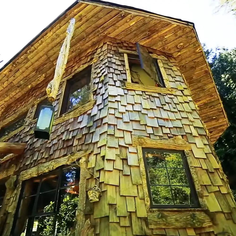Rustic wooden house with shingled exterior in a forested outdoor setting