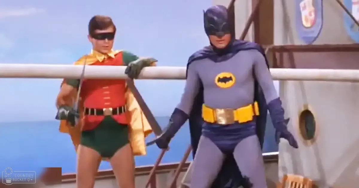A scene from 'Batman' with Robin and Batman, set on the deck of a ship under clear blue skies during daytime.