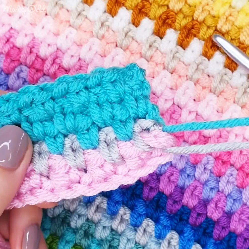 A colorful crocheted fabric with various patterns and stitches indoors.