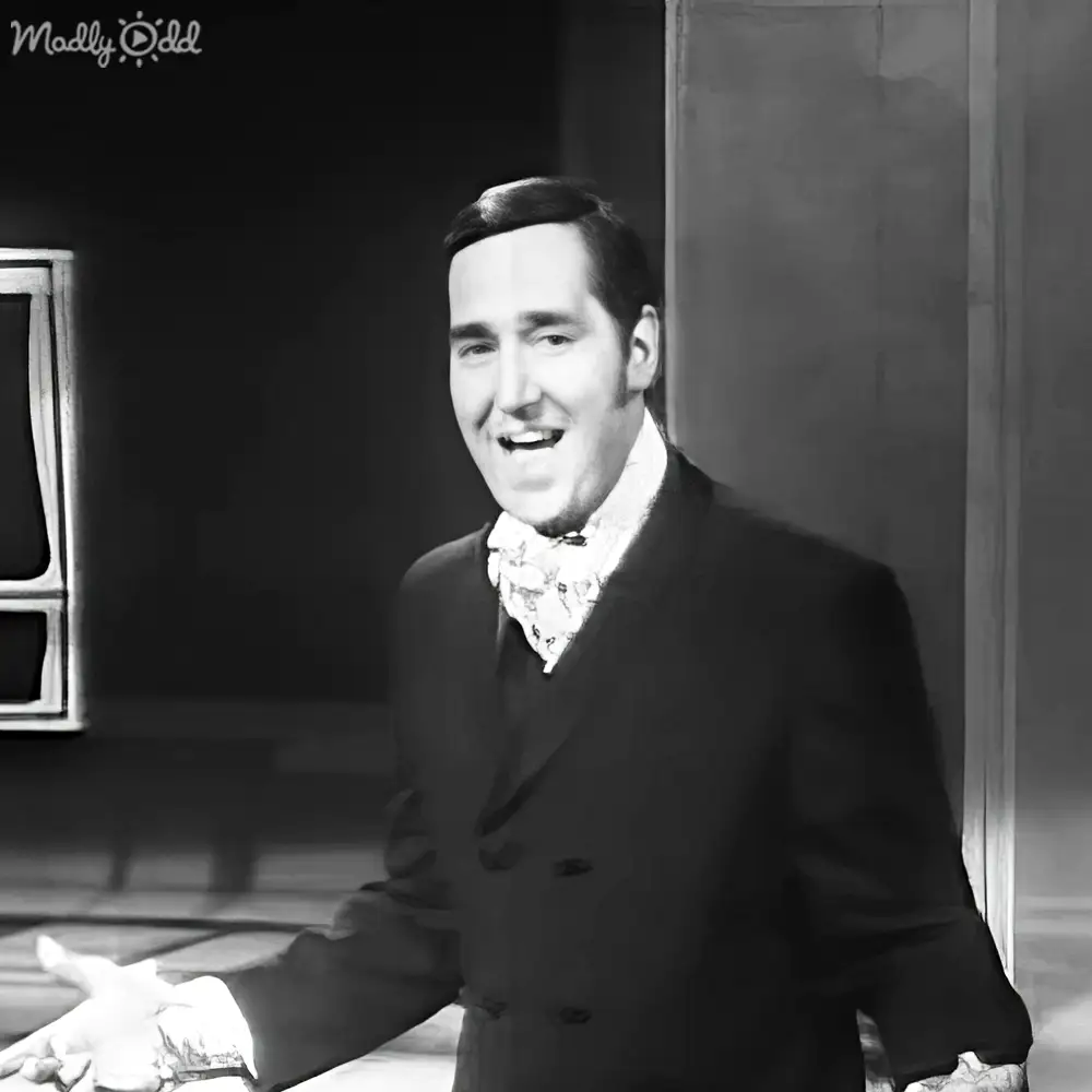 Adult male wearing a formal double-breasted suit jacket with high collar, likely from late 19th or early 20th century, indoors in a room possibly used for formal occasions.