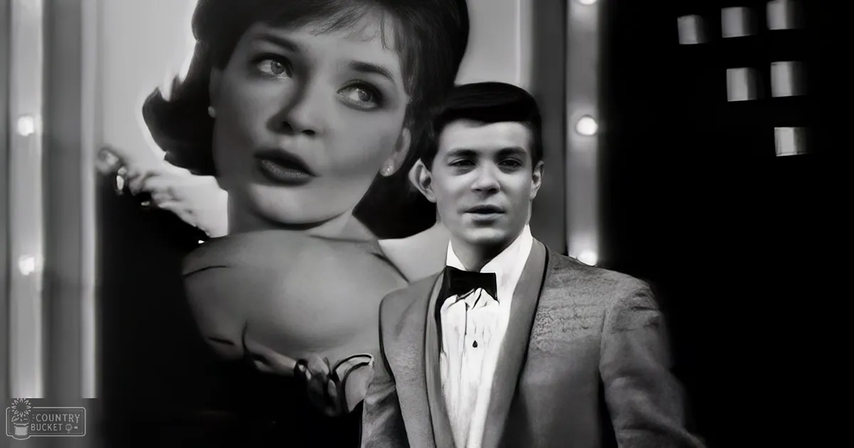 A young adult male in a formal suit with a bow tie stands indoors, possibly near an entranceway.