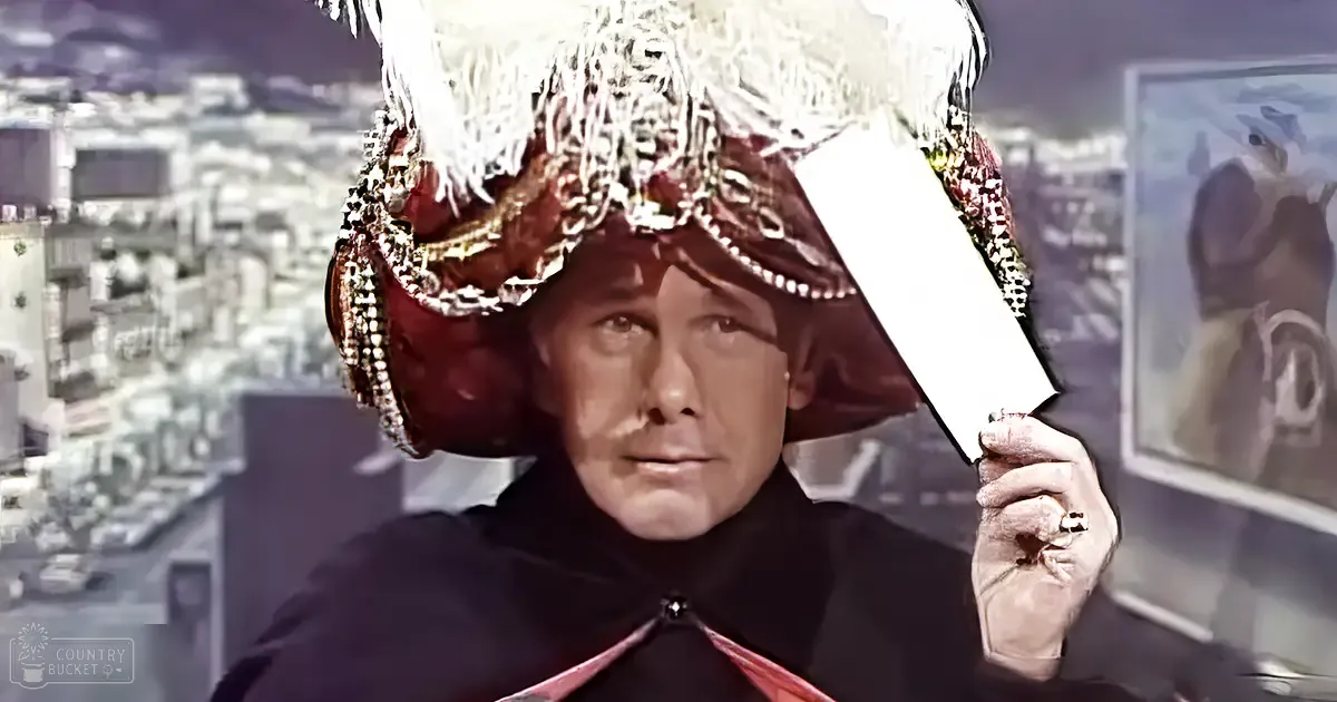 A middle-aged male character wearing a dark red or maroon, loose-fitting robe with a high collar and ornate hat stands indoors against an urban backdrop.