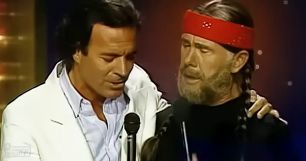 A comedic duo performing on stage at an awards ceremony, with one wearing a white blazer over a light blue button-up shirt and another in a black jacket or hoodie with a red headband, set against the backdrop of dimly lit stage microphones.