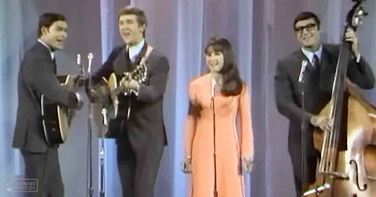 A musical performance with young adults in formal attire against a plain blue curtain background.