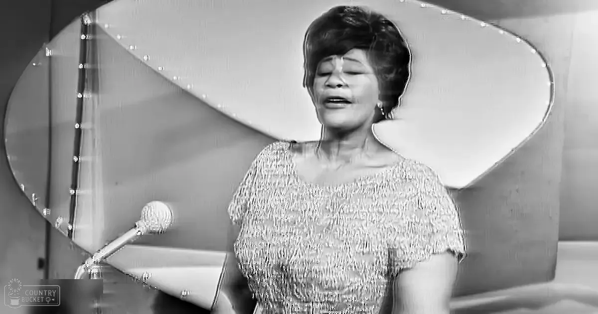 A middle-aged woman singing in a professional recording studio with ornate mirror and microphone stand.