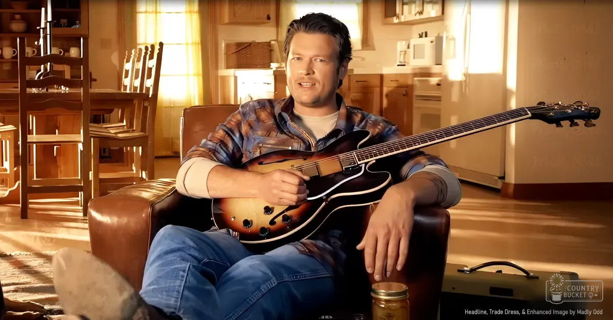 An adult male in a cozy living room or kitchen area, wearing a plaid shirt with rolled-up sleeves and blue jeans, seated on a brown leather armchair near a wooden dining table.
