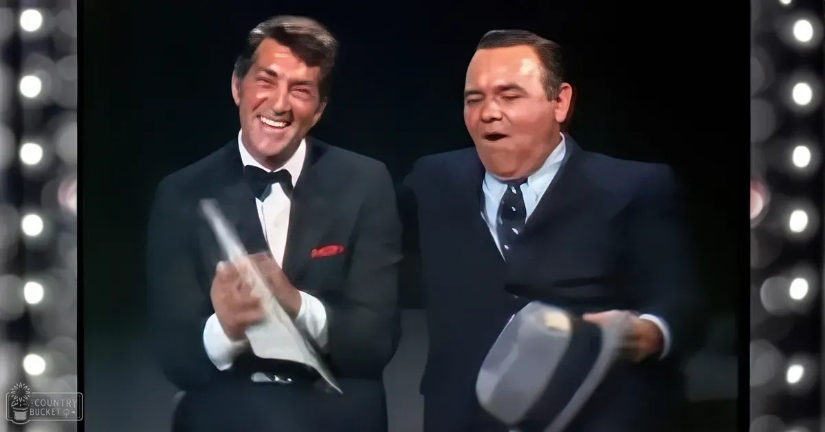 Middle-aged male performers in a formal stage setting, holding scripts; dark indoor performance environment with circular lights and mid-20th century attire.