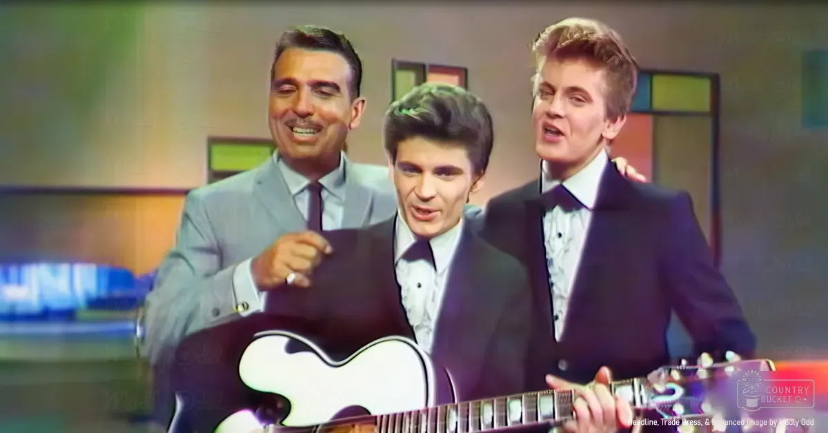 A musical performance scene with three young adult men dressed formally indoors under studio lighting.