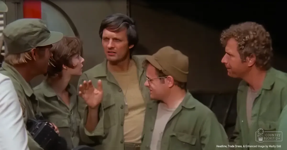 A group of adults in an indoor setting, possibly a military or scientific facility, wearing jackets and t-shirts.